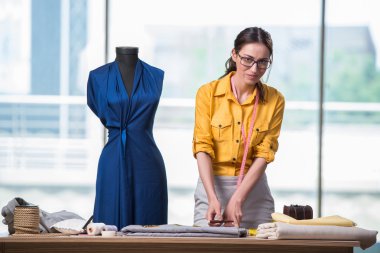 Kadın terzi yeni elbiseler üzerinde çalışıyor.