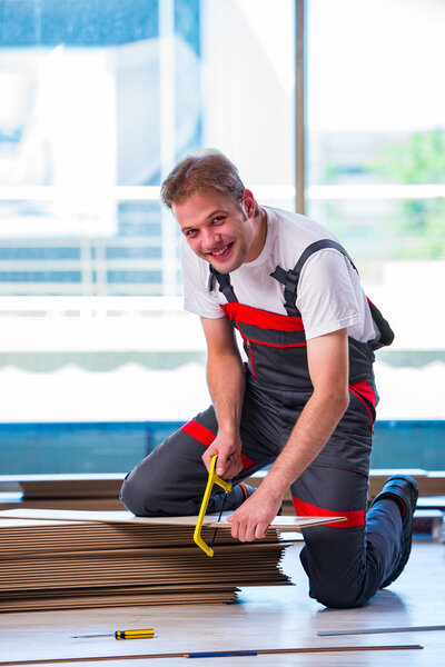 Man laying laminate flooring in construction concept