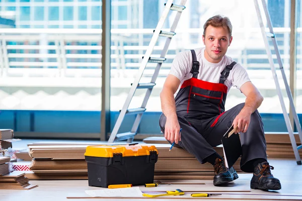 Homem que estabelece piso laminado no conceito de construção — Fotografia de Stock