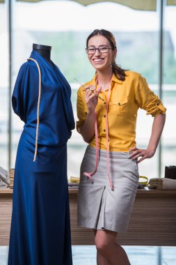 Kadın terzi yeni elbiseler üzerinde çalışıyor.