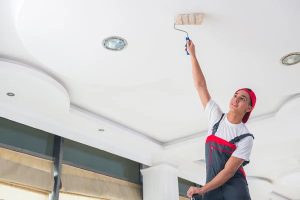 Young painter painting the ceiling in construction concept