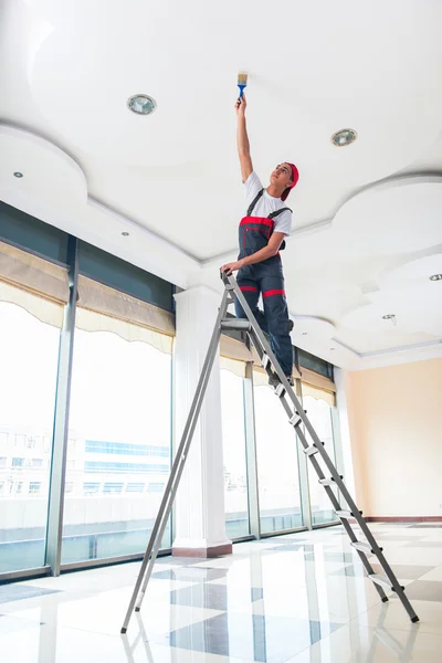 Joven pintor pintando el techo en concepto de construcción —  Fotos de Stock