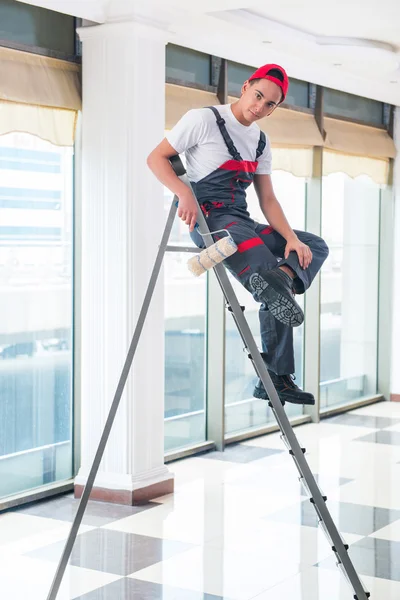 Jovem pintor pintando o teto no conceito de construção — Fotografia de Stock