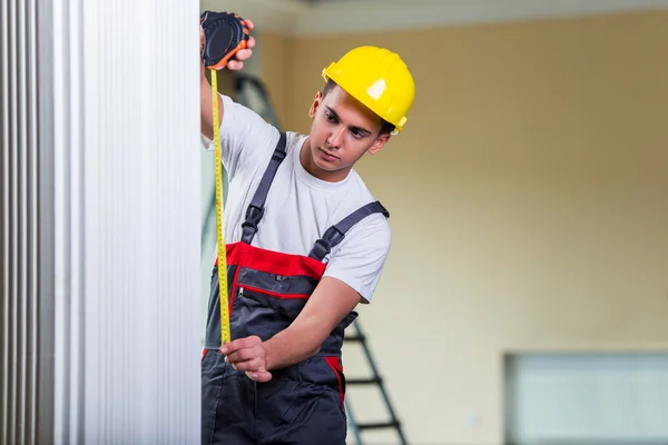 Joven reparador con cinta métrica trabajando en reparaciones — Foto de Stock