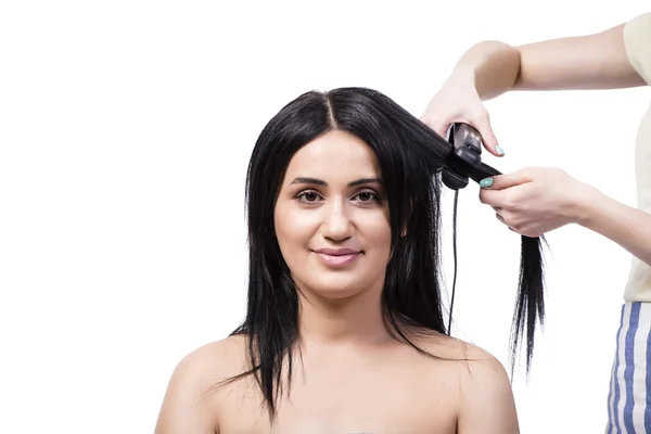 Νεαρή γυναίκα να πάρει ισιώματος μαλλιών που απομονώνονται σε λευκό — Φωτογραφία Αρχείου