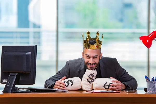 Empresário com coroa e sacos de dinheiro no escritório — Fotografia de Stock