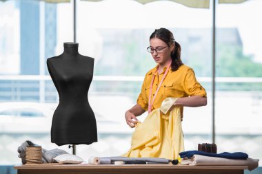 Kadın terzi yeni elbiseler üzerinde çalışıyor.