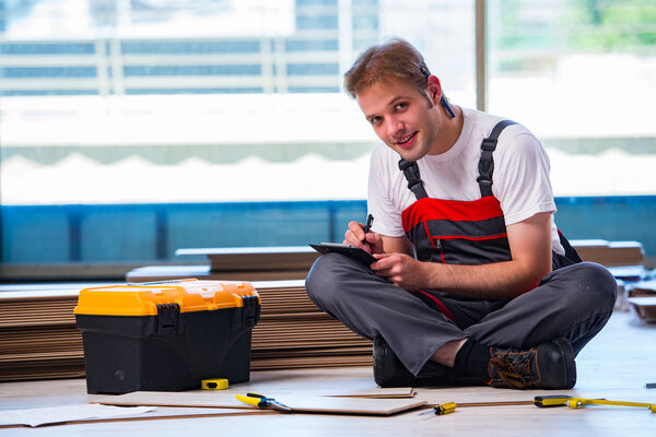 Man laying laminate flooring in construction concept