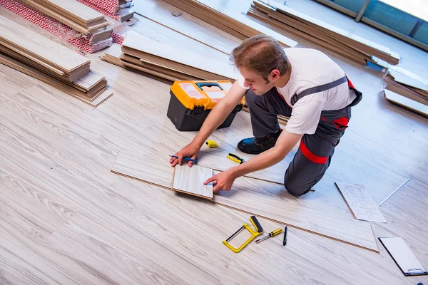 Homem que estabelece piso laminado no conceito de construção — Fotografia de Stock