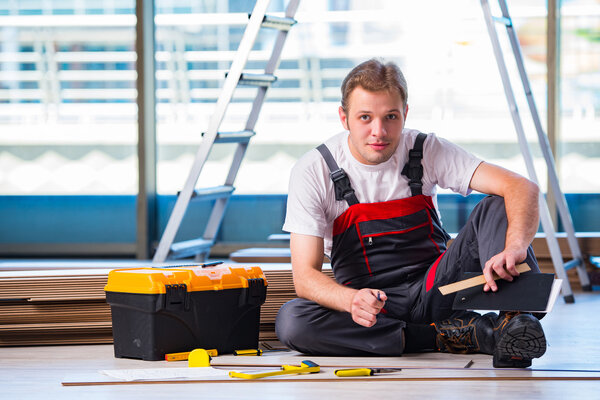 Man laying laminate flooring in construction concept