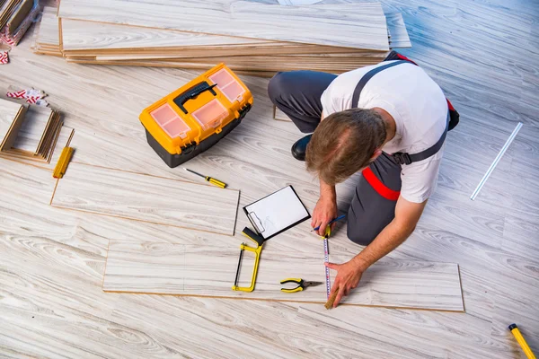 Homem que estabelece piso laminado no conceito de construção — Fotografia de Stock