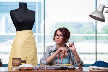 Kadın terzi yeni elbiseler üzerinde çalışıyor.