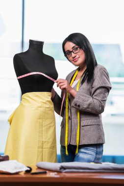 Kadın terzi yeni elbiseler üzerinde çalışıyor.