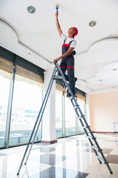 Jovem pintor pintando o teto no conceito de construção — Fotografia de Stock