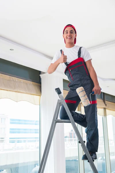 Jovem pintor pintando o teto no conceito de construção — Fotografia de Stock