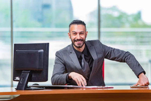 Homem de negócios feliz sentado na mesa — Fotografia de Stock