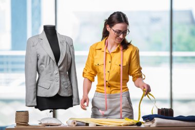 Kadın terzi yeni elbiseler üzerinde çalışıyor.