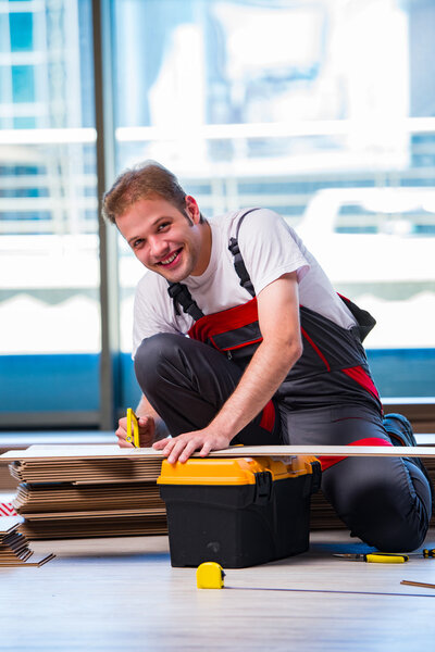 Man laying laminate flooring in construction concept