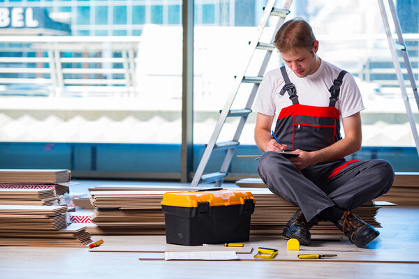 Man laying laminate flooring in construction concept