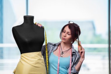 Kadın terzi yeni elbiseler üzerinde çalışıyor.