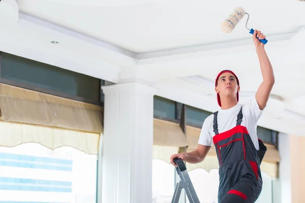 Jovem pintor pintando o teto no conceito de construção — Fotografia de Stock