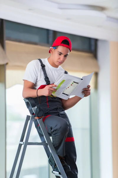 Jovem reparador verificando os desenhos antes de iniciar o trabalho — Fotografia de Stock