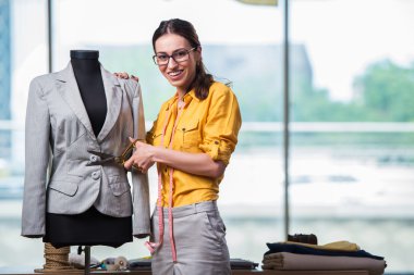 Kadın terzi yeni elbiseler üzerinde çalışıyor.