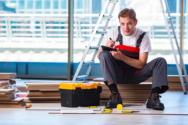 Homem que estabelece piso laminado no conceito de construção — Fotografia de Stock