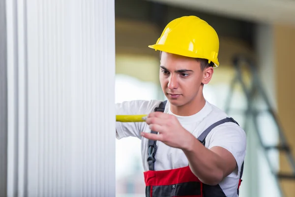 Joven reparador con cinta métrica trabajando en reparaciones —  Fotos de Stock