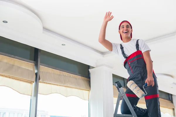 Jovem pintor pintando o teto no conceito de construção — Fotografia de Stock