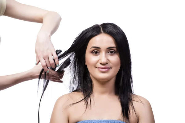 Jonge vrouw aan haar stijltang geïsoleerd op wit — Stockfoto