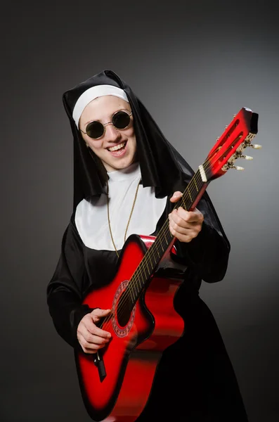 Freira engraçada com guitarra vermelha tocando — Fotografia de Stock