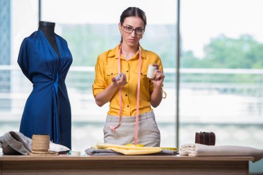 Kadın terzi yeni elbiseler üzerinde çalışıyor.