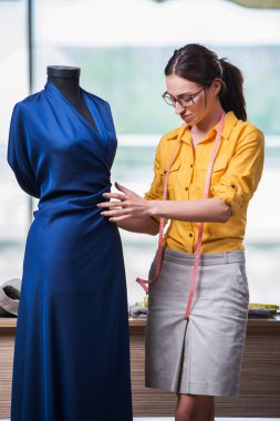 Kadın terzi yeni elbiseler üzerinde çalışıyor.