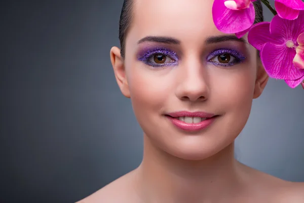 Mujer joven en concepto de belleza con flor de orquídea — Foto de Stock