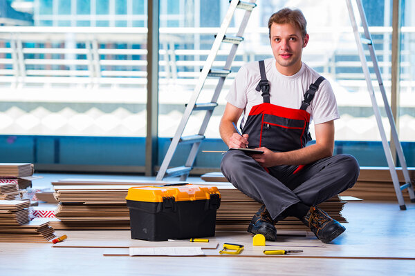 Man laying laminate flooring in construction concept