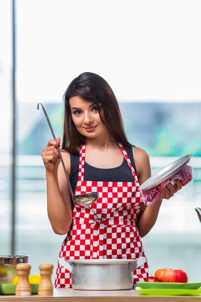 Female cook preparing soup in brightly lit kitchen — Stock Photo, Image