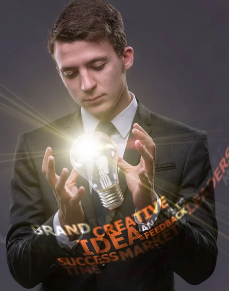 Young businessman with light bulb in idea concept — Stock Photo, Image