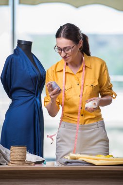 Kadın terzi yeni elbiseler üzerinde çalışıyor.