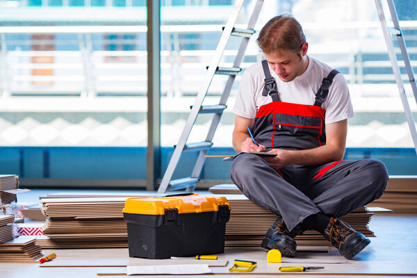 Man laying laminate flooring in construction concept