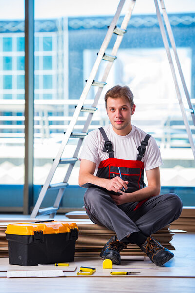 Man laying laminate flooring in construction concept