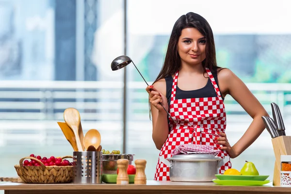 Vrouwelijke kok bereiden soep in fel verlicht keuken — Stockfoto