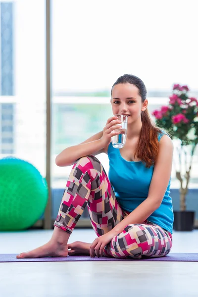 Mujer joven bebiendo agua en gimnasio concepto de salud — Foto de Stock