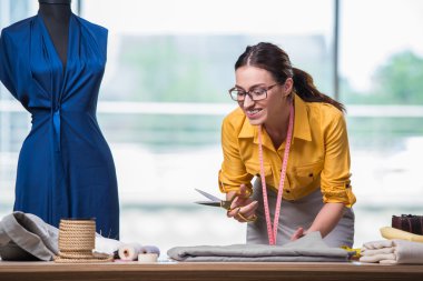 Kadın terzi yeni elbiseler üzerinde çalışıyor.