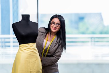 Kadın terzi yeni elbiseler üzerinde çalışıyor.