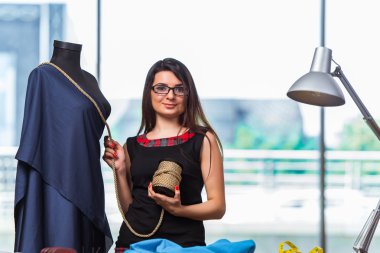 Kadın terzi yeni elbiseler üzerinde çalışıyor.