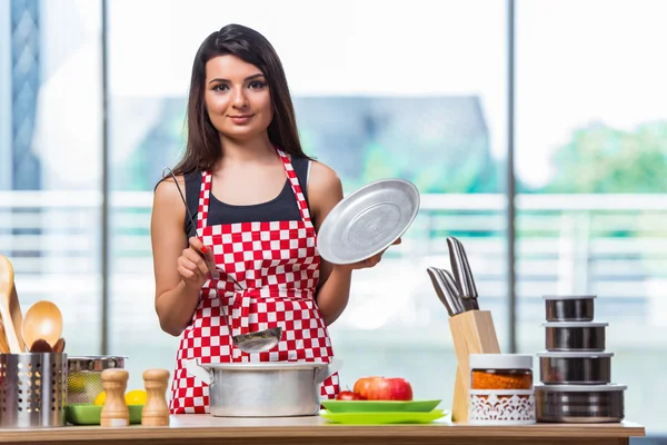 Female cook preparing soup in brightly lit kitchen — Stock Photo, Image