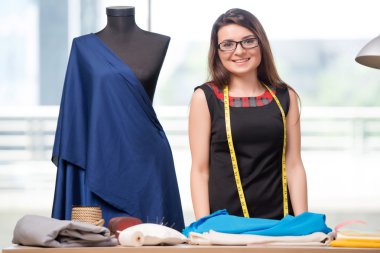 Kadın terzi yeni elbiseler üzerinde çalışıyor.