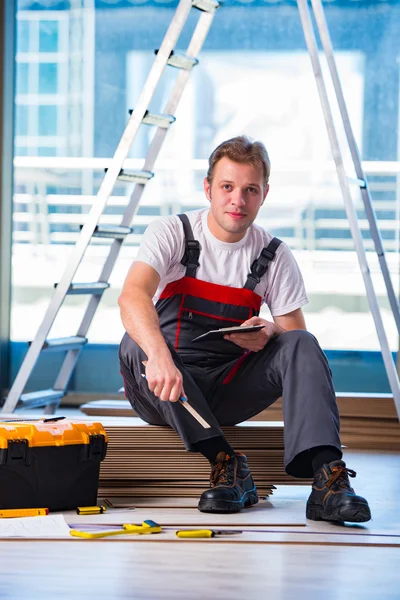 Homem que estabelece piso laminado no conceito de construção — Fotografia de Stock
