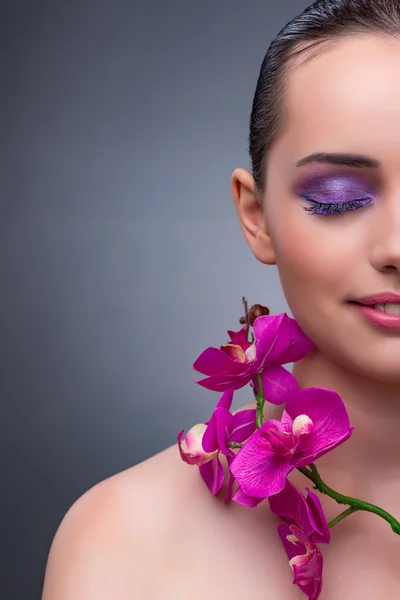 Mujer joven en concepto de belleza con flor de orquídea — Foto de Stock